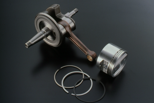 La foto mostra il pistone e il gruppo biella-albero a gomito (composito) del monocilindrico Rotax. Per portare al perno di manovella l’olio che fuoriesce lateralmente da un cuscinetto di banco si impiega un convogliatore centrifugo, ben visibile nell’immagine