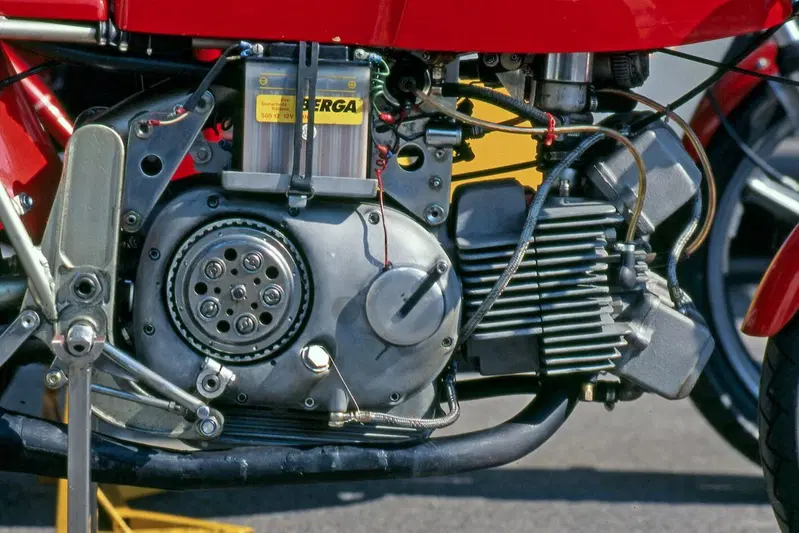 -Foto dal lato destro del motore della Aermacchi 250 bialbero. Rispetto al modello di serie, con distribuzione ad aste e bilancieri, non cambia praticamente nulla, a eccezione della testa, costituita da una fusione completamente nuova. Si noti la doppia accensione
