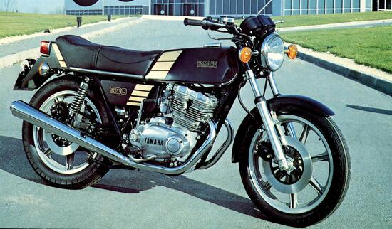 Alla Yamaha va il merito di avere messo in produzione, nel 1974, la prima moto di serie con distribuzione bialbero a quattro valvole. Denominata XS 500, aveva un motore a due cilindri paralleli dotato di due alberi ausiliari di equilibratura. L’albero a gomiti monolitico aveva le manovelle a 180° e lavorava su bronzine. Questa è una delle ultime versioni