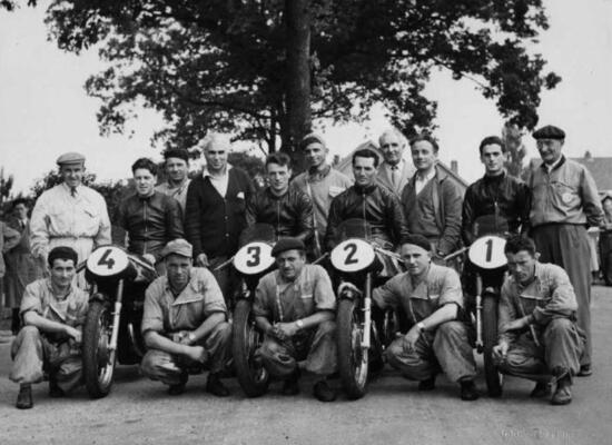 Lo squadrone Gilera ad Assen per il G.P. d’Olanda vinto da Duke. In piedi da sinistra: Sandro Colombo, Geoff Duke, Il meccanico Cazzaniga e il direttore sportivo Piero Taruffi, Giuseppe Colnago, Ettore Villa della Catene Regina e Giuseppe Gilera. Poi Renato Guaschino, concessionario Gilera ad Asti, Umberto Masetti e Pierino Bernasconi direttore commerciale Gilera. In ginocchio il meccanico Colombo, l’autista Galbusera ed i meccanici Fumagalli, Tremolada e Meda. Sulla numero 2, Alfredo Milani