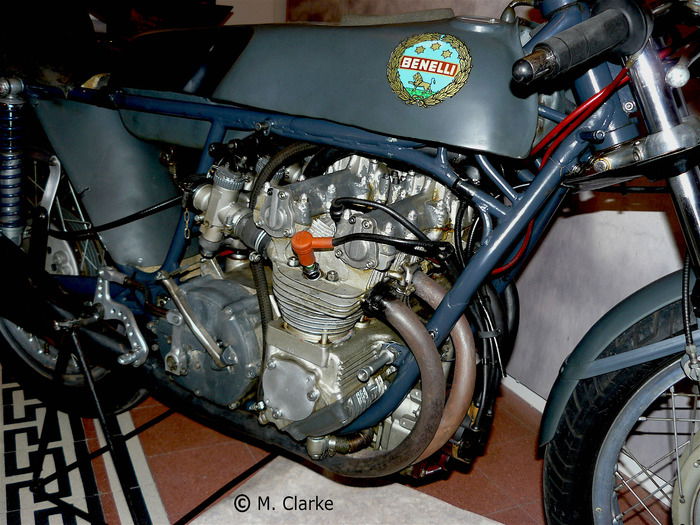 La Benelli 250 aveva cilindri singoli ed era dotata di due teste, tra le quali passava la cartella nella quale erano alloggiati gli ingranaggi di comando della distribuzione bialbero. Il basamento era costituito da una unica grande fusione e l’albero a gomiti veniva inserito dal basso, attraverso una apertura praticata anteriormente, il cui coperchio è parzialmente visibile nella foto