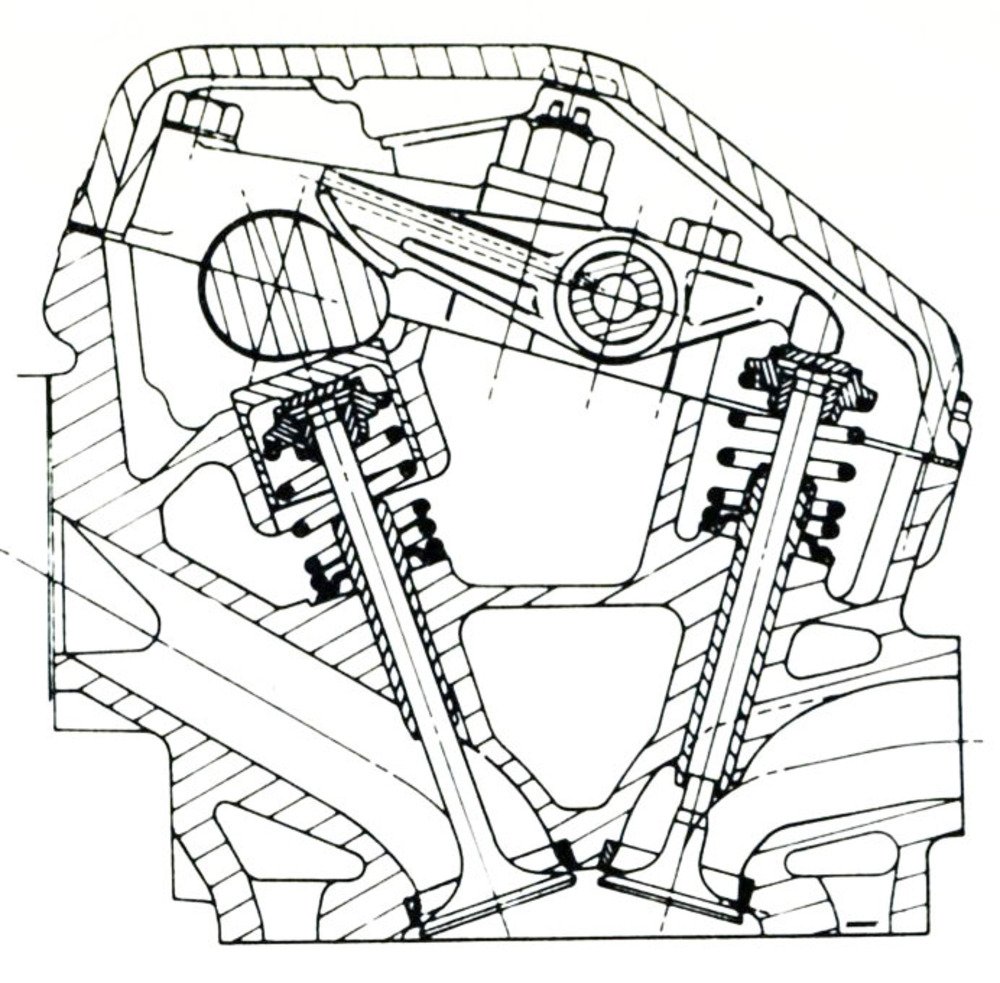 Questa sezione della testa consente di osservare chiaramente la disposizione degli organi della distribuzione nel motore Triumph. La medesima camma comandava sia una punteria (per muovere la valvola di aspirazione) che un bilanciere a due bracci